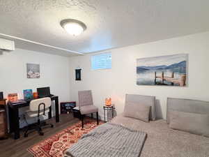 Bedroom featuring a textured ceiling, dark wood-style flooring, and a desk