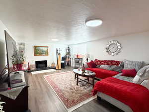 Living room with a textured ceiling, a fireplace, and wood finished floors