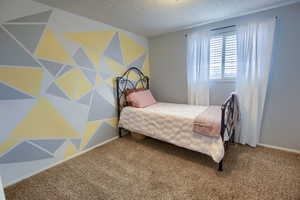 Carpeted bedroom with a textured ceiling and baseboards