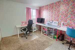 Office space with wallpapered walls and dark speckled floor