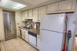 Kitchen featuring white appliances, decorative backsplash, and light tile patterned floors