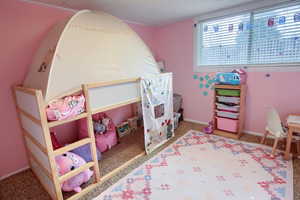 Playroom with light colored carpet and a textured ceiling
