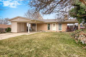 Single story home featuring an attached carport, a front lawn, brick siding, and concrete driveway