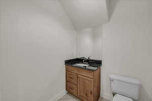 Bathroom featuring vanity, light tile patterned floors, and lofted ceiling