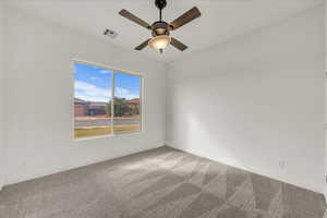 Empty room with light colored carpet and a ceiling fan