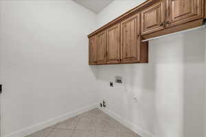 Laundry room with gas dryer hookup, light tile patterned floors, cabinet space, washer hookup, and hookup for an electric dryer