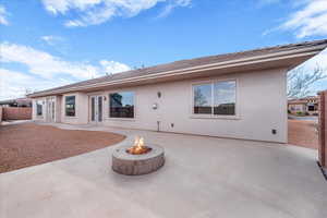 Rear view of house featuring a patio area, stucco siding, an outdoor fire pit, and french doors