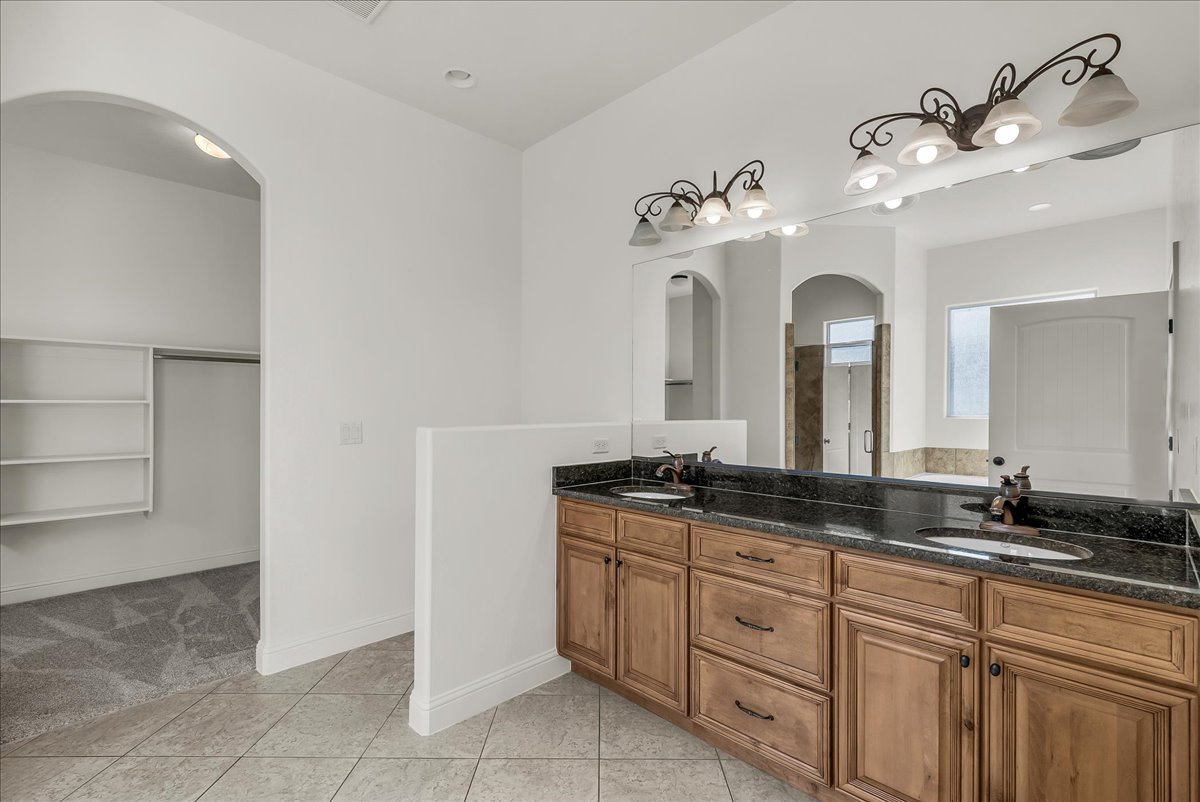 Bathroom featuring a spacious closet, double vanity, light tile patterned flooring, and recessed lighting