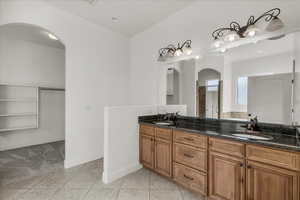 Bathroom featuring a spacious closet, double vanity, light tile patterned flooring, and recessed lighting