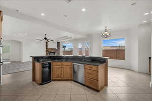 Kitchen featuring wood finish cabinets, a tray ceiling, open floor plan, a fireplace, and dark stone counters