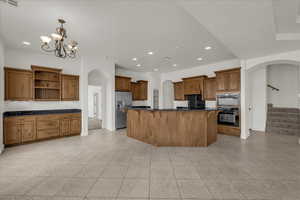 Kitchen featuring arched walkways, wood finish cabinetry, and a spacious island