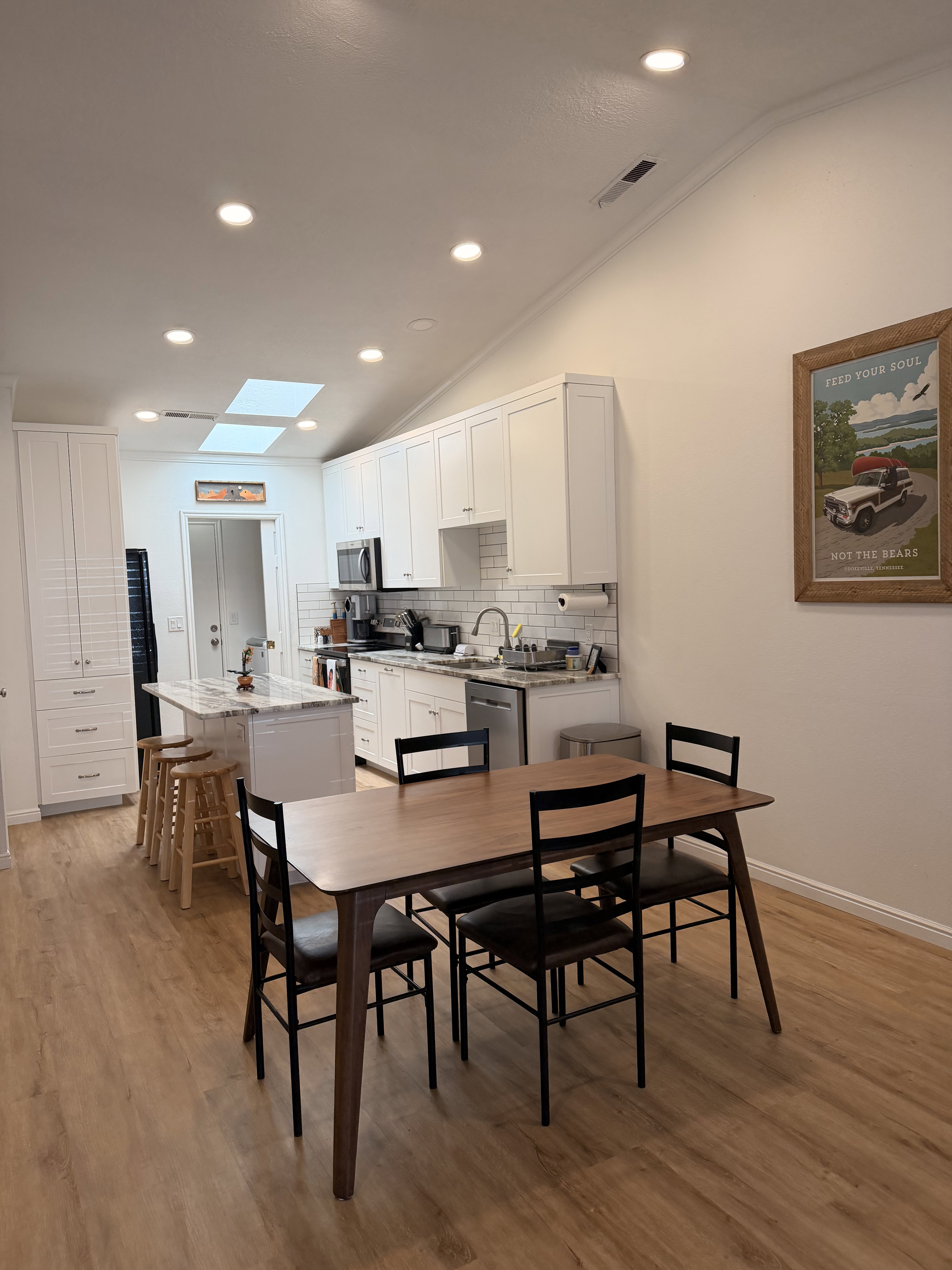 Dining space featuring light wood-style floors, vaulted ceiling, a skylight, and recessed lighting