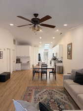 Living area featuring vaulted ceiling, light wood-style flooring, ceiling fan, and recessed lighting