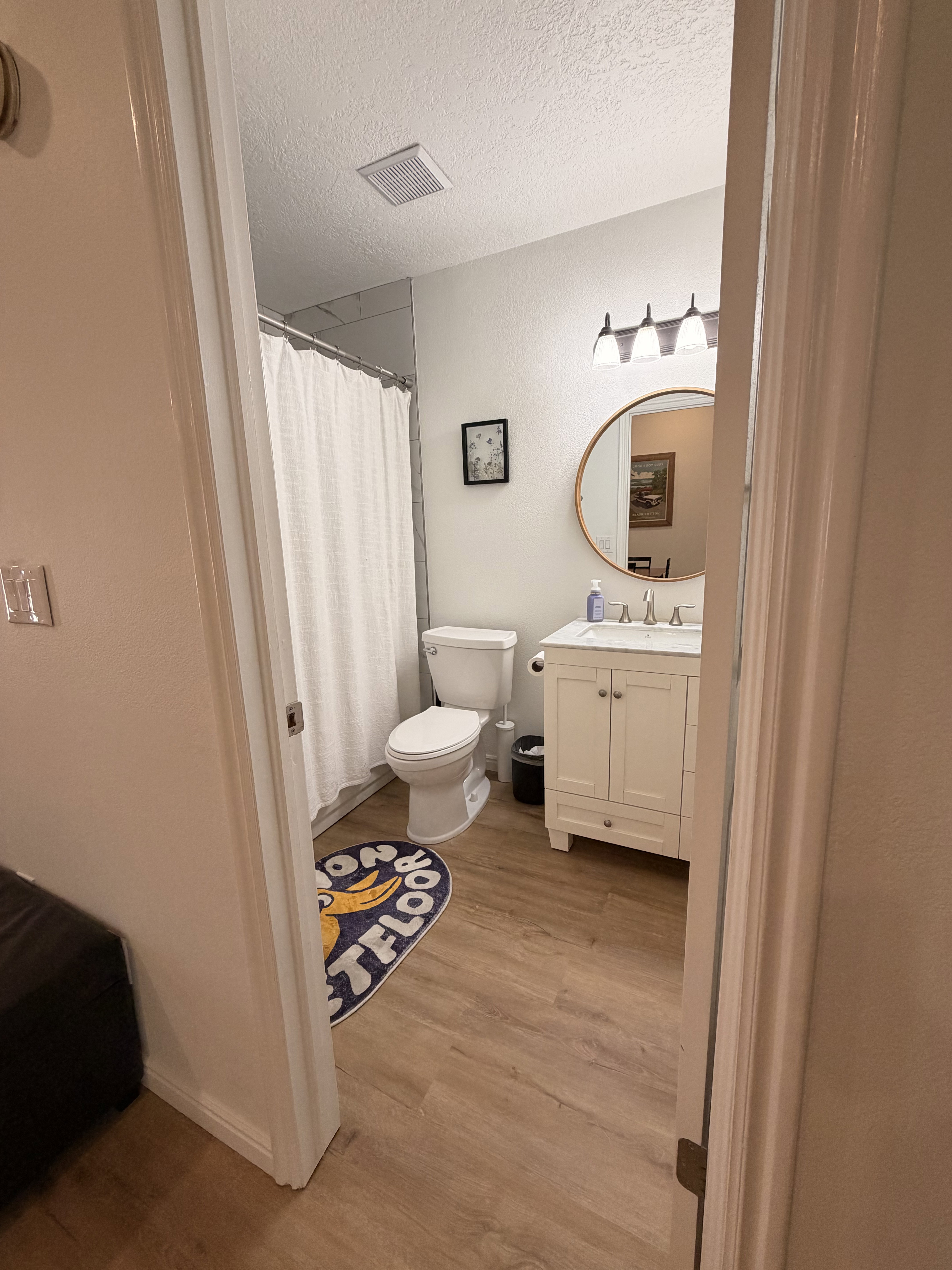 Full bath featuring vanity, light wood-style floors, a shower with shower curtain, and a textured ceiling