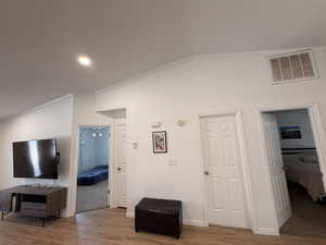 Hallway with vaulted ceiling, ornamental molding, light wood-style flooring, and recessed lighting