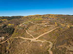 Aerial view of sparsely populated area with property parcel outlined and a mountain backdrop