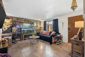 Living room featuring a desk, wooden walls, and light wood-type flooring