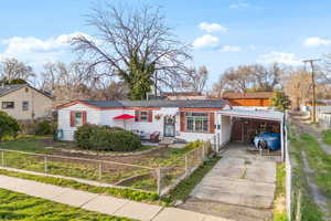 View of front of house featuring a fenced front yard, a carport, driveway, and a shingled roof