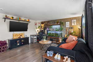 Living room featuring wood finished floors, wood walls, and a fireplace