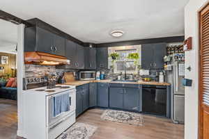 Kitchen with stainless steel appliances, butcher block counters, light wood-style floors, and decorative backsplash