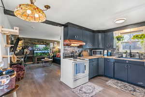 Kitchen featuring white range with electric stovetop, dark wood-style floors, stainless steel microwave, and decorative backsplash