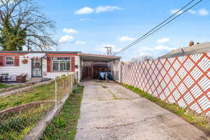 Exterior space featuring a fenced front yard, an attached carport, and concrete driveway