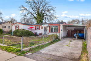 View of front of house featuring an attached carport, a fenced front yard, and driveway