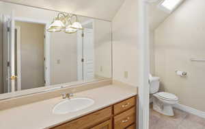 Bathroom featuring vanity, light tile patterned floors, vaulted ceiling, and a chandelier