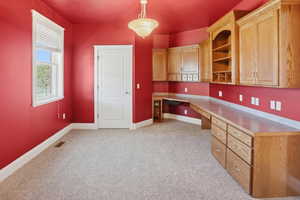 Unfurnished office featuring built in desk and light carpet