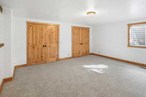 Unfurnished bedroom featuring two closets and carpet