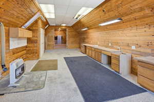 Bonus Room above Garage Miscellaneous room featuring wood walls, heating unit, light colored carpet, and a paneled ceiling