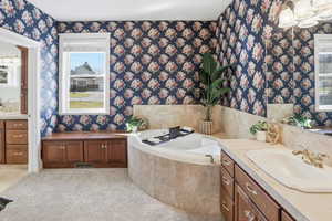Primary Suite Full bath featuring vanity, a garden tub, and light colored carpet