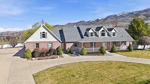 Front of house with a mountain view, covered porch, brick siding, and curved driveway
