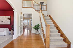 Staircase featuring a high ceiling, hardwood / wood-style flooring, arched walkways, and decorative columns