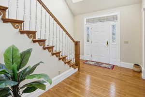 Entrance foyer with hardwood / wood-style floors and vaulted ceiling