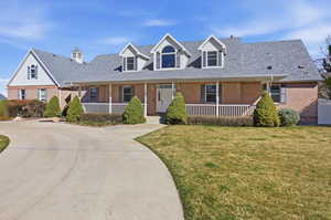 Front of house with brick siding, a porch, a front yard, and a shingled roof