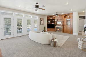 Living area featuring light carpet, a ceiling fan, a tiled fireplace, and recessed lighting