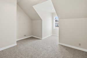 Additional bedroom space featuring light colored carpet and vaulted ceiling