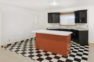 Family Room Kitchen with dark cabinetry, light countertops, glass fronted cabinets, light flooring, and a kitchen island