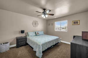 Bedroom with ceiling fan and dark carpet