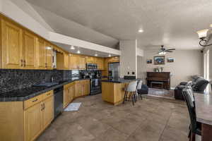 Kitchen featuring open floor plan, a ceiling fan, stainless steel appliances, a breakfast bar, and recessed lighting