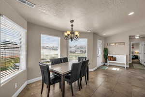Tiled dining space featuring hanging lights and baseboards