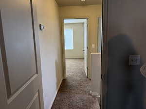 Corridor featuring dark carpet and baseboards