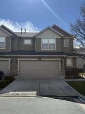 View of front of house featuring stucco siding, driveway, brick siding, a garage, and board and batten siding