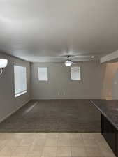 Basement with light colored carpet, ceiling fan, and a textured ceiling