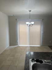 Unfurnished dining area featuring a textured ceiling and suspended lighting