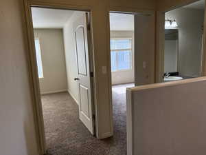 Hallway with light carpet and baseboards