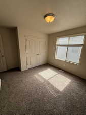 Unfurnished bedroom featuring carpet flooring, a textured ceiling, and a closet