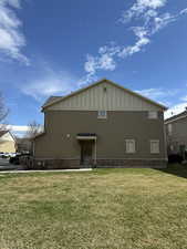 Front Door view of property featuring brick siding, board and batten siding, and a lawn