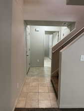Hallway featuring baseboards and light tile patterned flooring